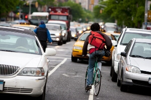 image of a bike carrier riding against traffic in a busy NYC street