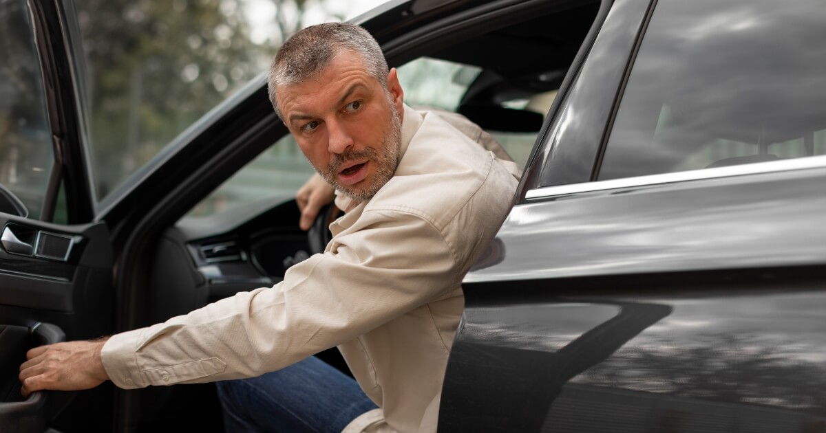 middle-aged man opening car door and looking back at traffic with concern