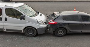 Rear end accident between a grey and black car.