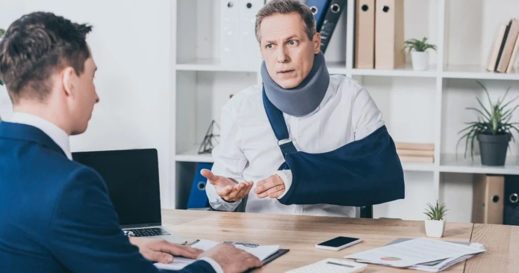 middle-aged man with his arm in a sling talking to a lawyer in a suit.