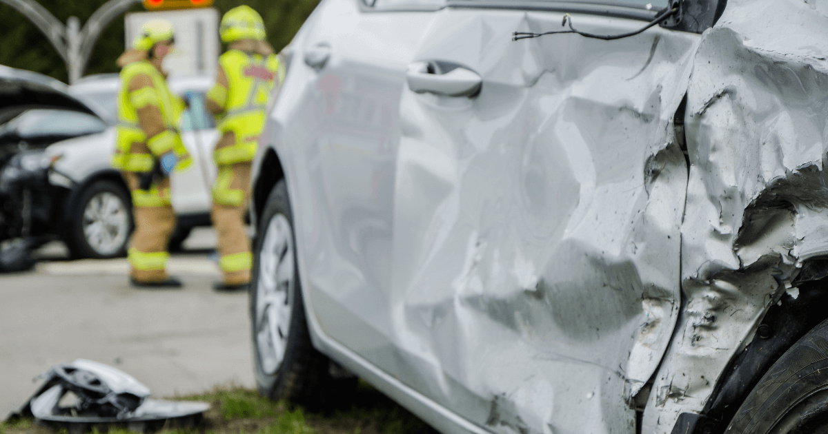 wrecked car; first responders in background