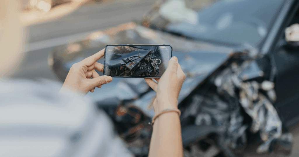person taking photos of car crash damage